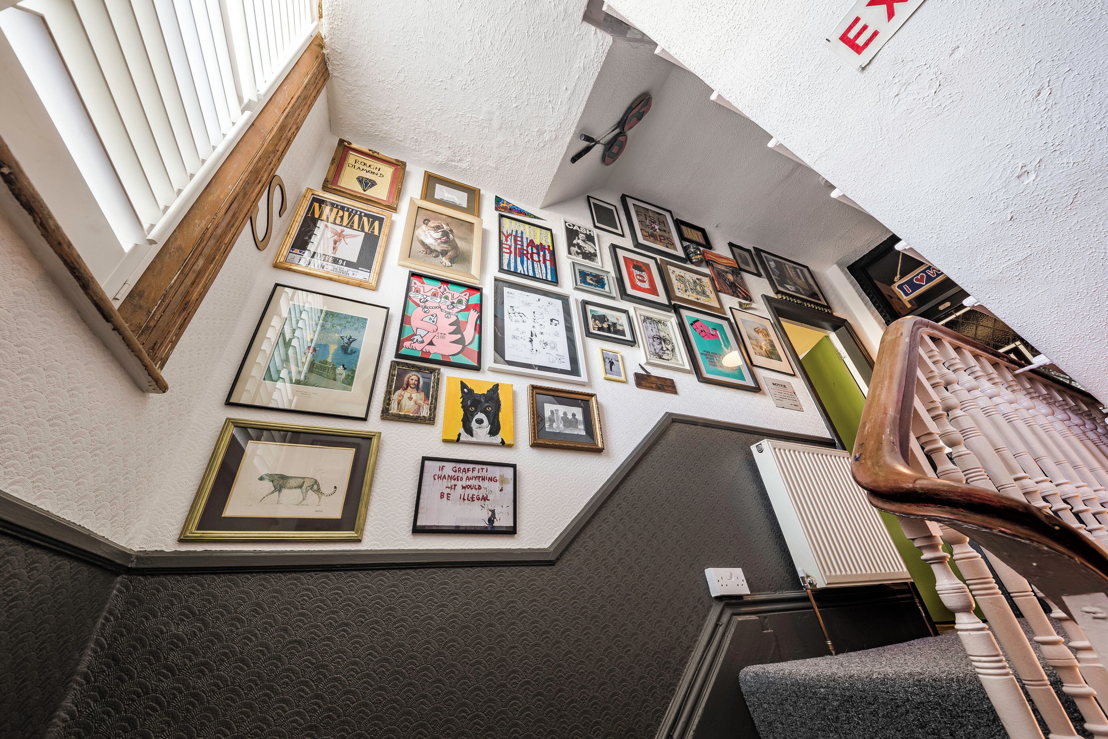 A wall with various framed artworks and a sign that reads "EXIT".