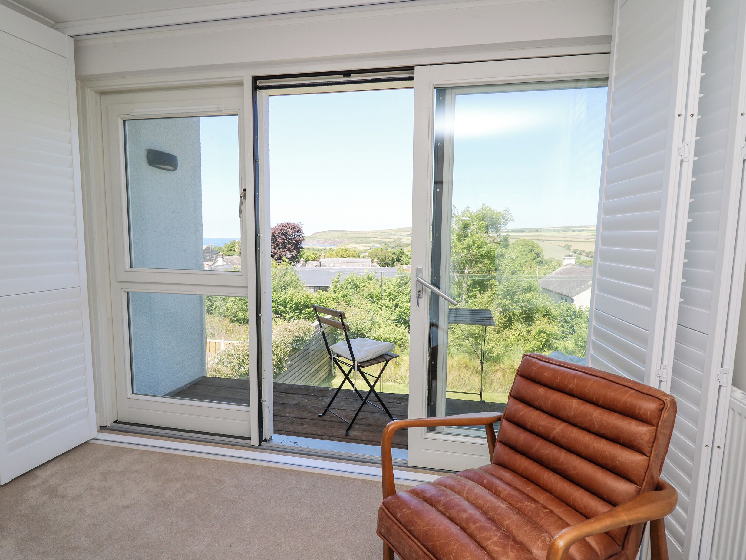 Une pièce dotée d’une porte-fenêtre coulissante donnant sur un balcon équipé d’une chaise et d’une table.