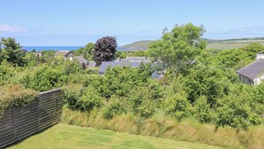 A residential area with houses, a large tree, and a view of the sea. - Cysgod Y Garn (Newport)