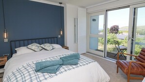 A bedroom with a bed, a chair, and a view through a sliding glass door. - Cysgod Y Garn (Newport)