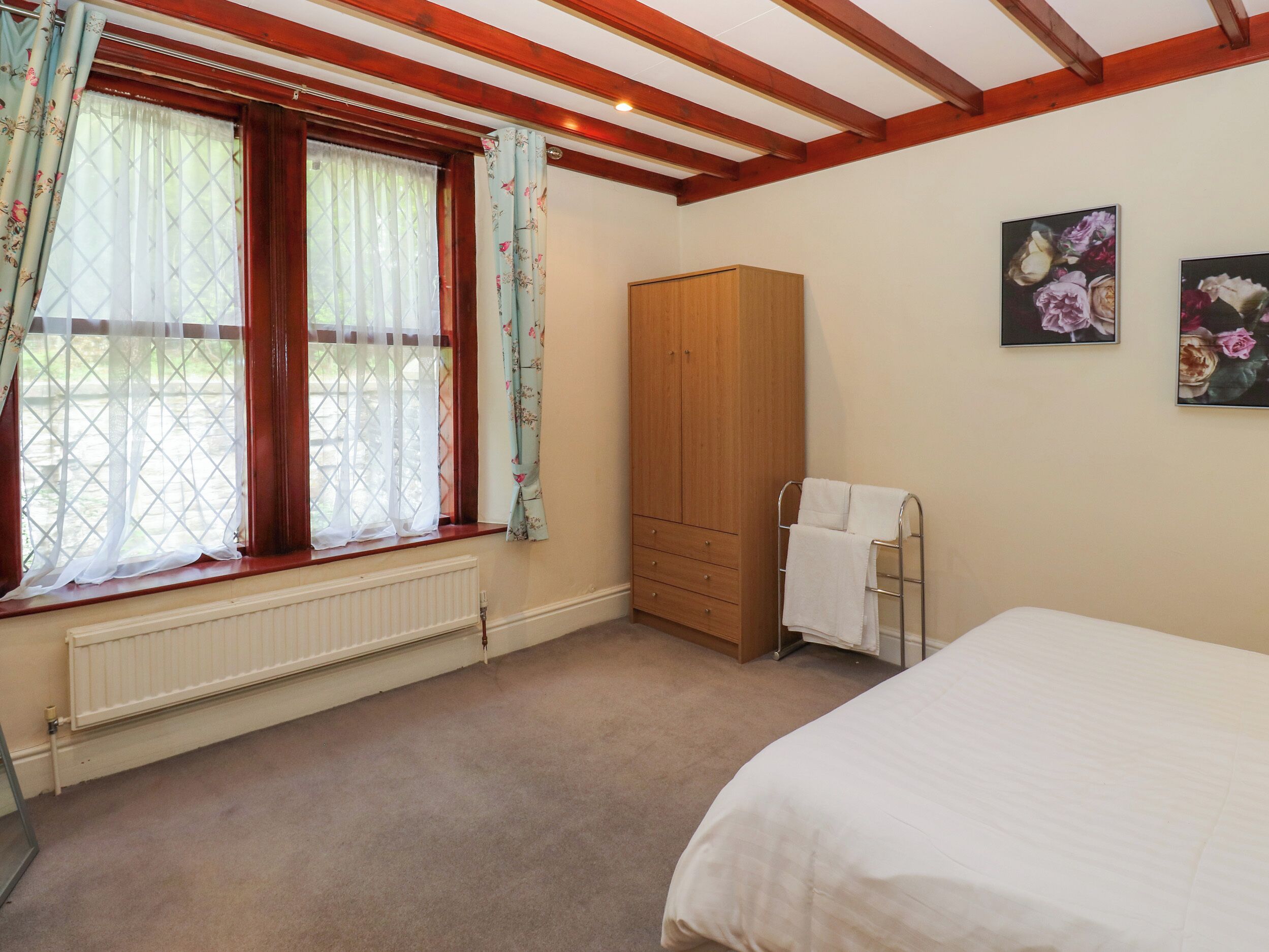 A bedroom with a bed, a wardrobe, a radiator, and a window with curtains.