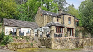A stone building with a sloped roof, a small porch, and a staircase leading to the entrance. - Highwood Lodge (Huddersfield)