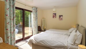 A bedroom with a bed, a desk, a chair, and a sliding glass door leading to an outdoor area. - Highwood Lodge (Huddersfield)