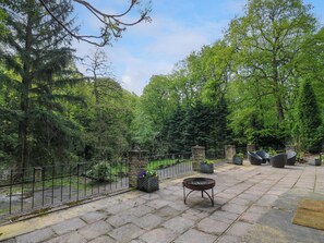 Un espace extérieur aménagé en terrasse, avec un sol en pierre, un foyer en métal et des sièges.