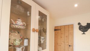 Een keuken met een houten deur en een kast met glazen deuren waarop keukengerei staat.