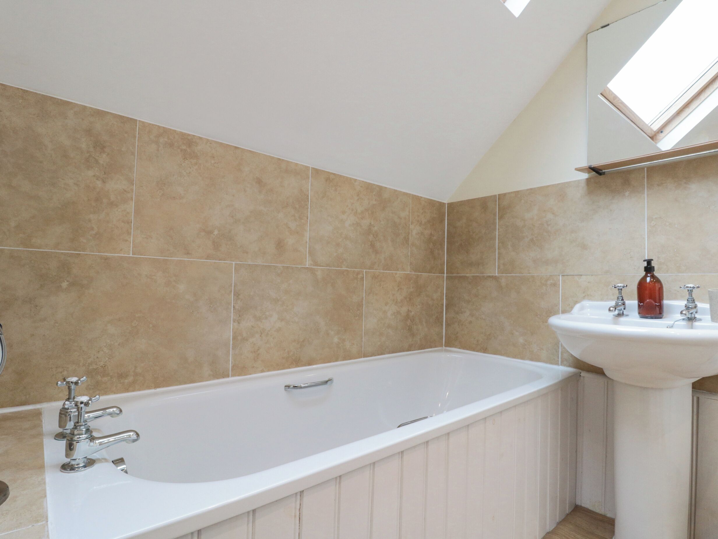 A bathroom with a bathtub, a sink, and a skylight.
