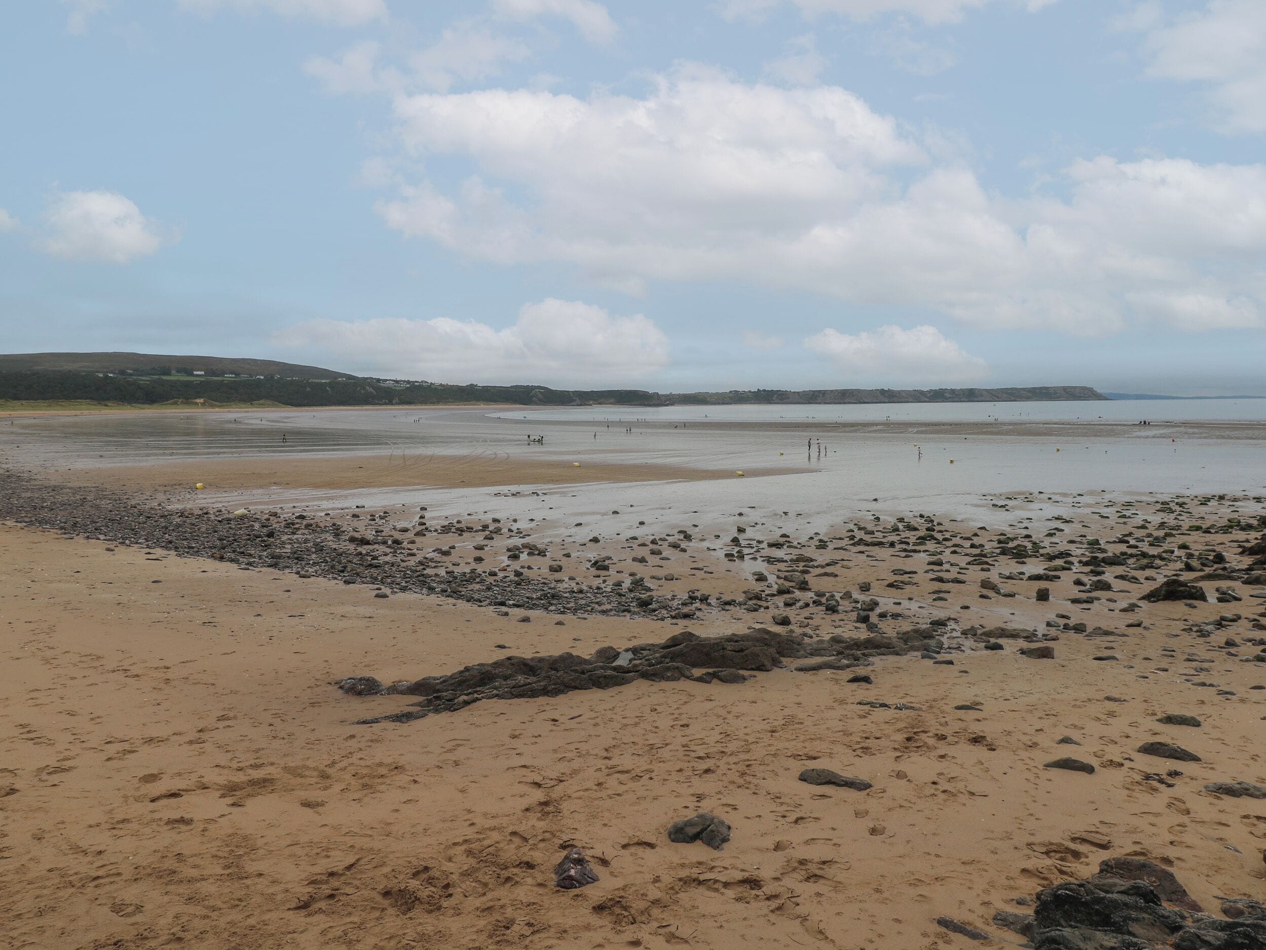 Une plage avec un rivage rocheux au premier plan et une mer calme à l’arrière-plan.