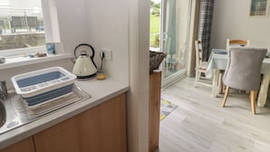 Eine moderne Küche mit Wasserkocher, Spüle und Fenster mit Blick auf einen Garten.