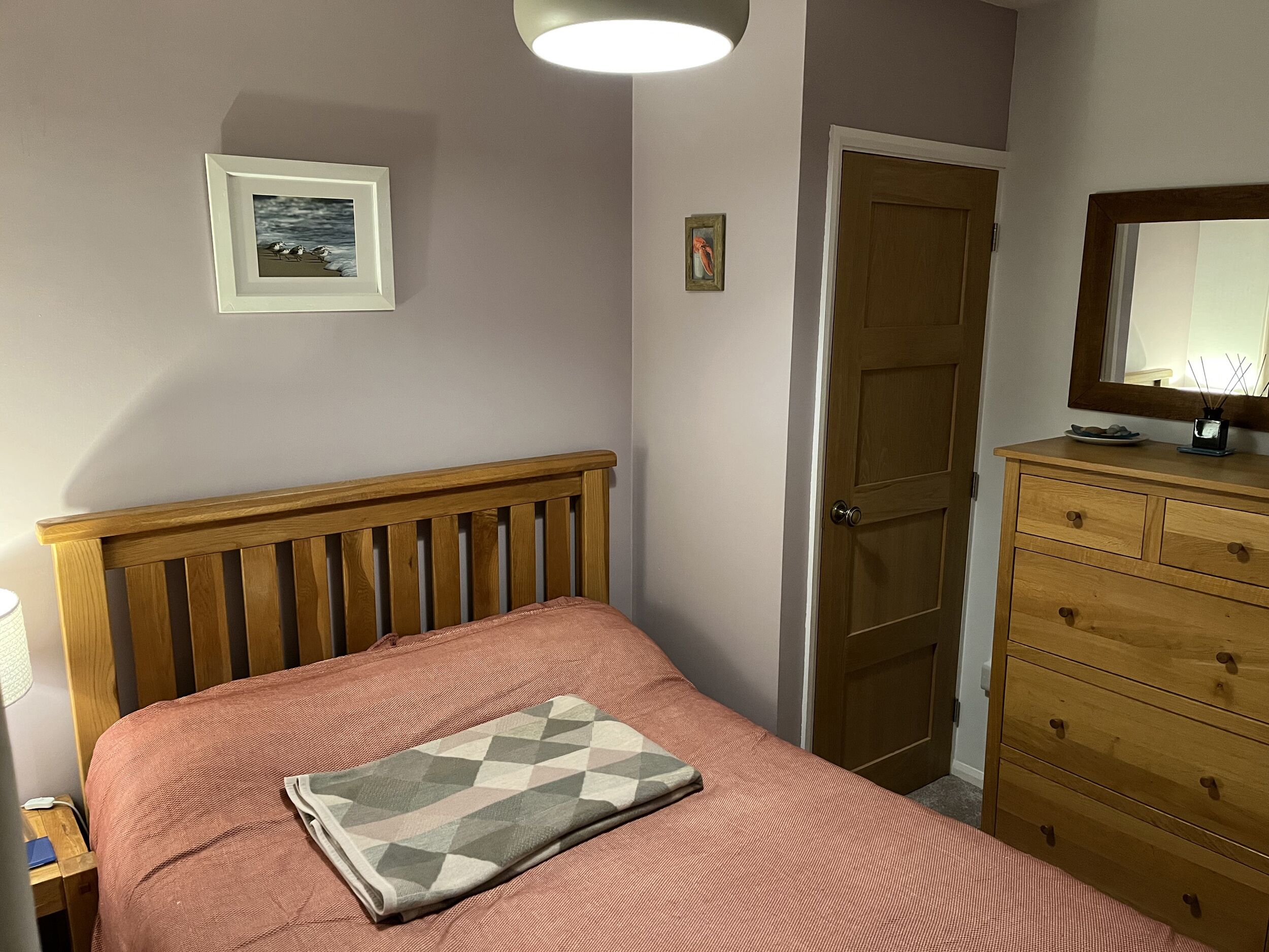 Ein Schlafzimmer mit einem hölzernen Bett, einem Schminktisch und einer Tür.