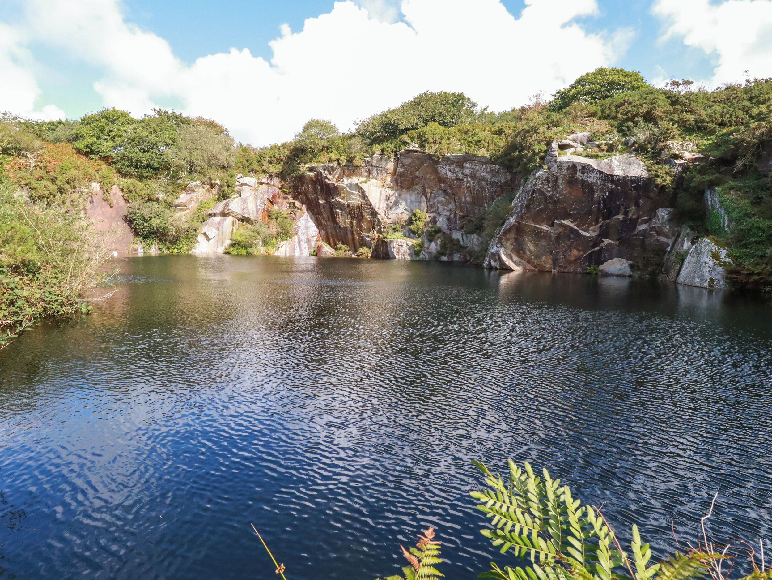 A serene lake surrounded by rocky cliffs and dense greenery.