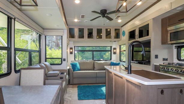 A compact RV kitchen with a dining area, a kitchenette, and a seating area with a view of greenery. - Tickeydoo, Tor Down Quarry (Bodmin)