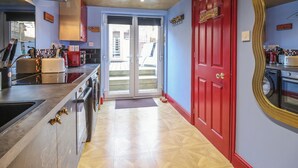 Une cuisine avec une porte rouge, un grand miroir et une vue sur l’extérieur.