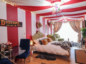 A room with a bed, a chair, a table, and a sign on the wall. - Circus Circus (Holywell)