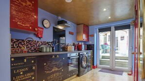 Une cuisine équipée d’un lave-linge, d’une horloge et d’un pare-feu en carreaux.