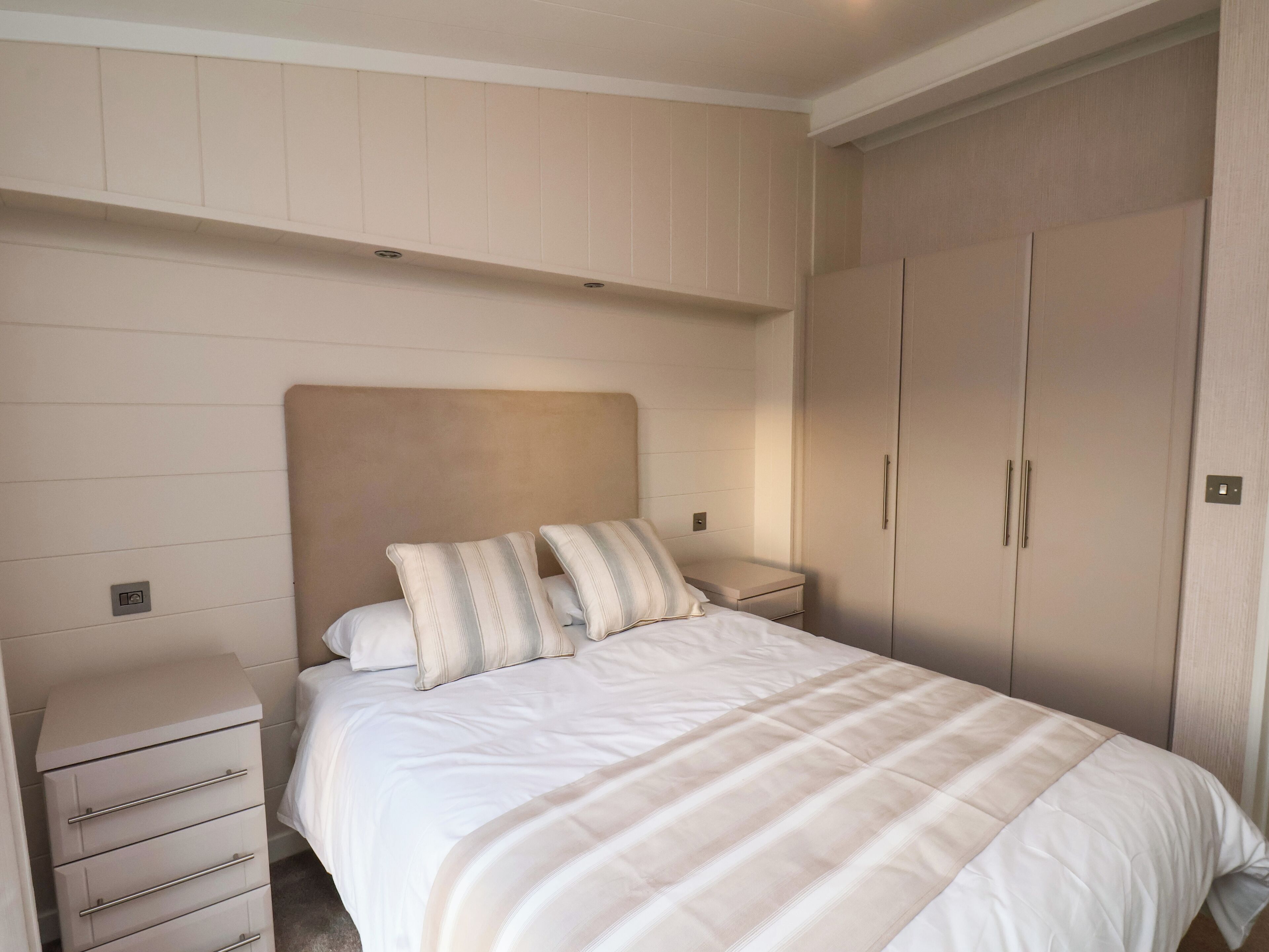 A bedroom with a bed, a nightstand, a dresser, and a wardrobe.