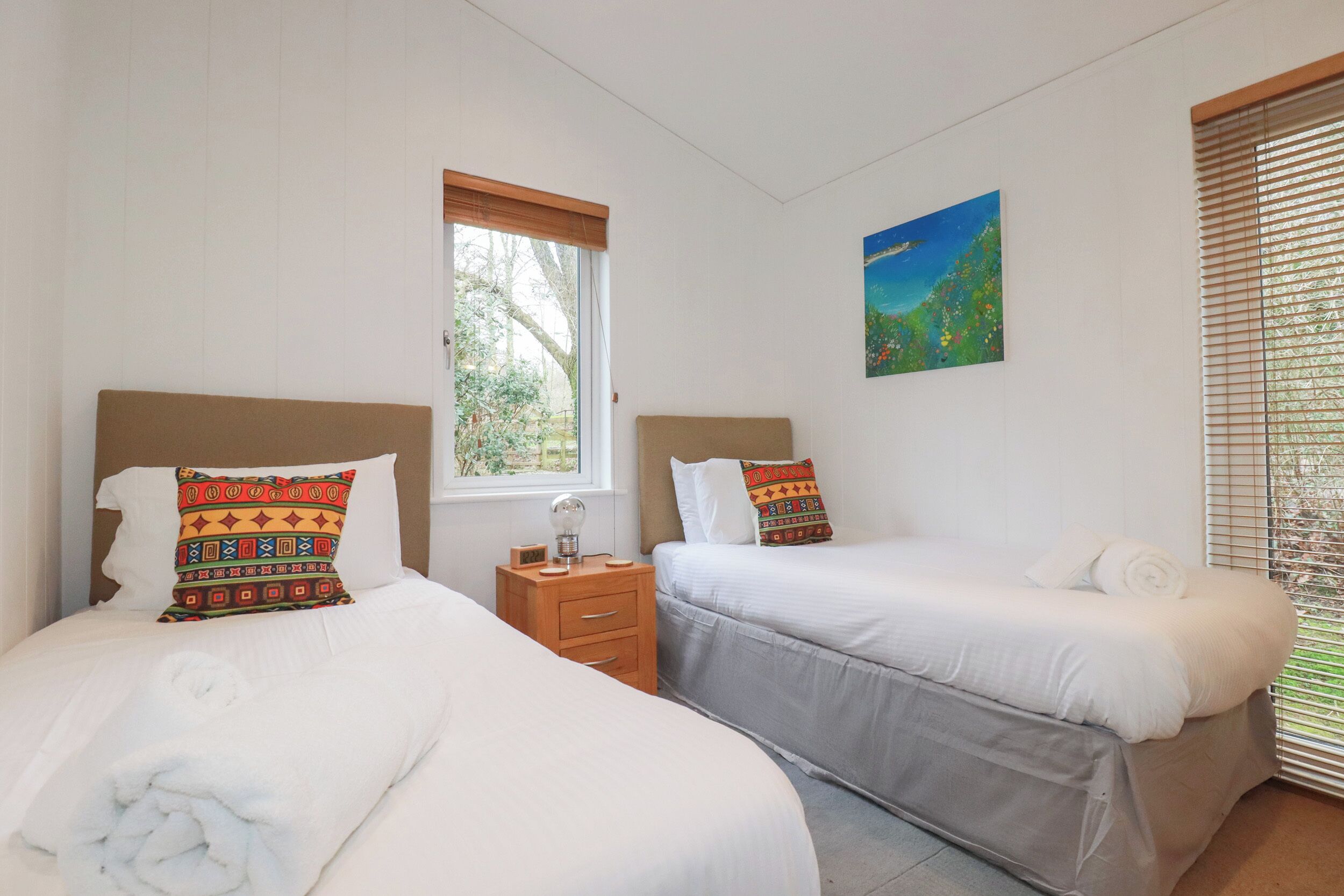 A bedroom with two beds, each with a pillow and a small bedside table.