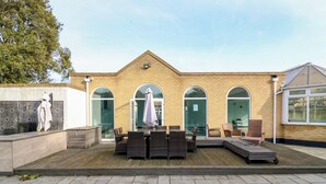 A modern building with a brick facade, large arched windows, and a patio area with outdoor furniture. - Maisonwyck (Canvey Island)