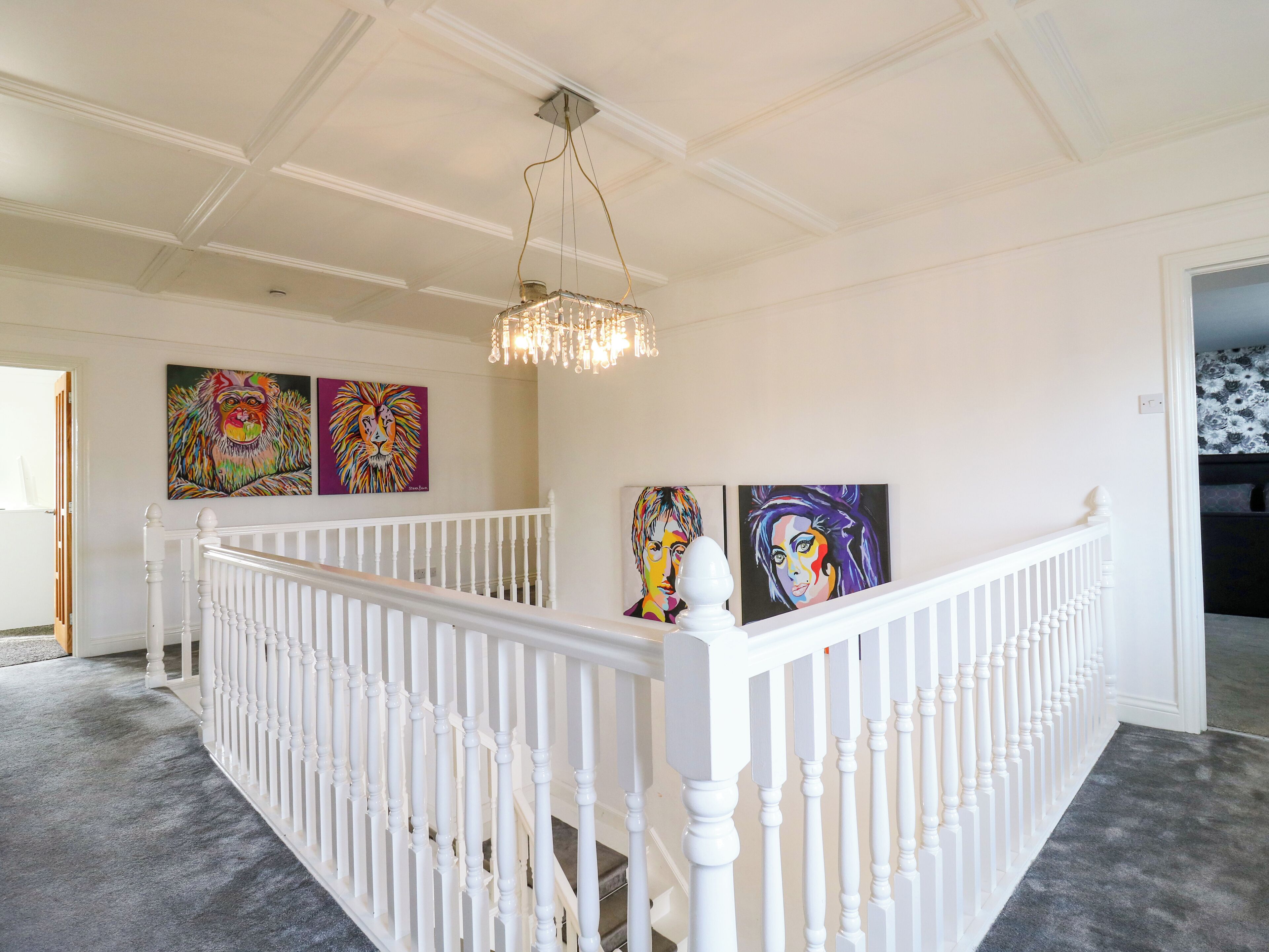 A staircase with white balusters and a chandelier.