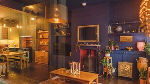 A cozy living room with a fireplace, wooden furniture, and decorative items. - Ballarat House (Margate)