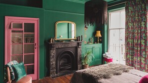 A room with a green wall, a pink door, a fireplace, a bed, and a window with curtains. - Ballarat House (Margate)