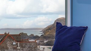 A view from a window overlooking a coastal landscape with rocky cliffs and a body of water. - Mavericks Wave (St. Agnes)