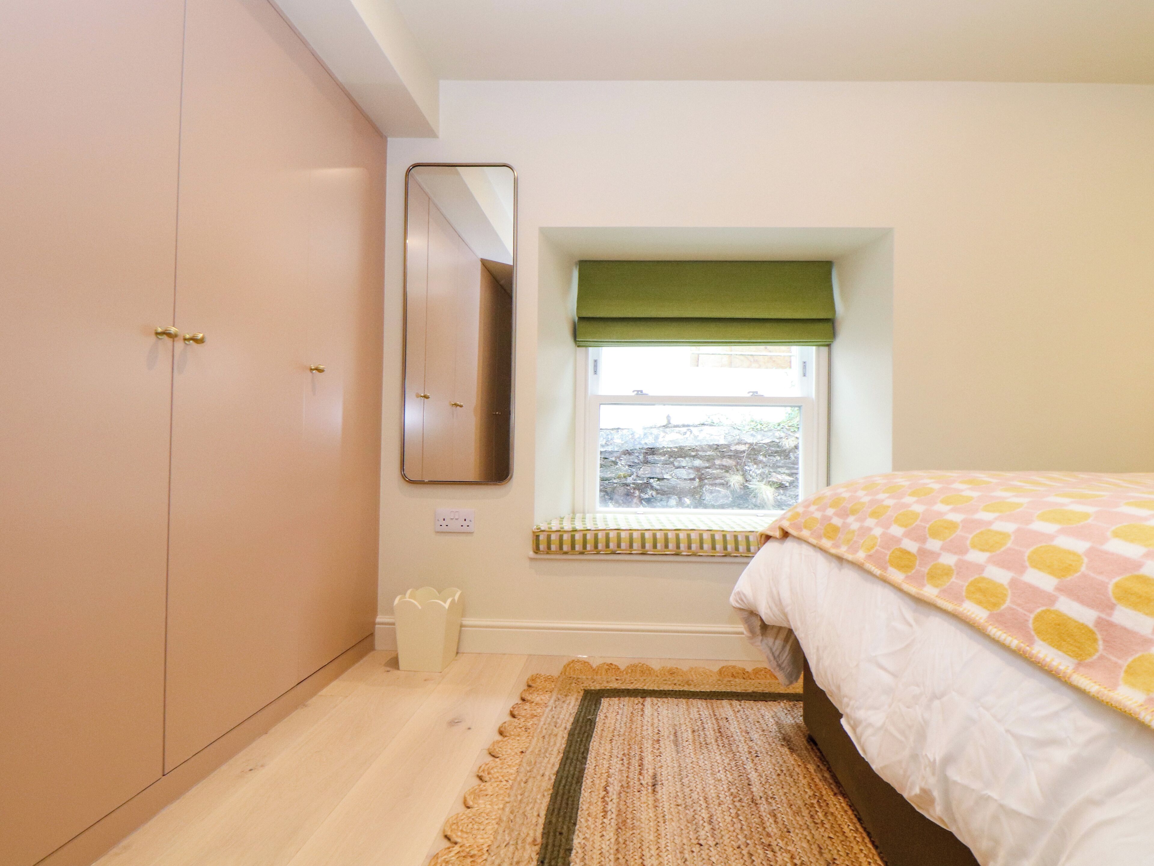 A bedroom with a bed, a window with a view, a wardrobe, and a mirror.