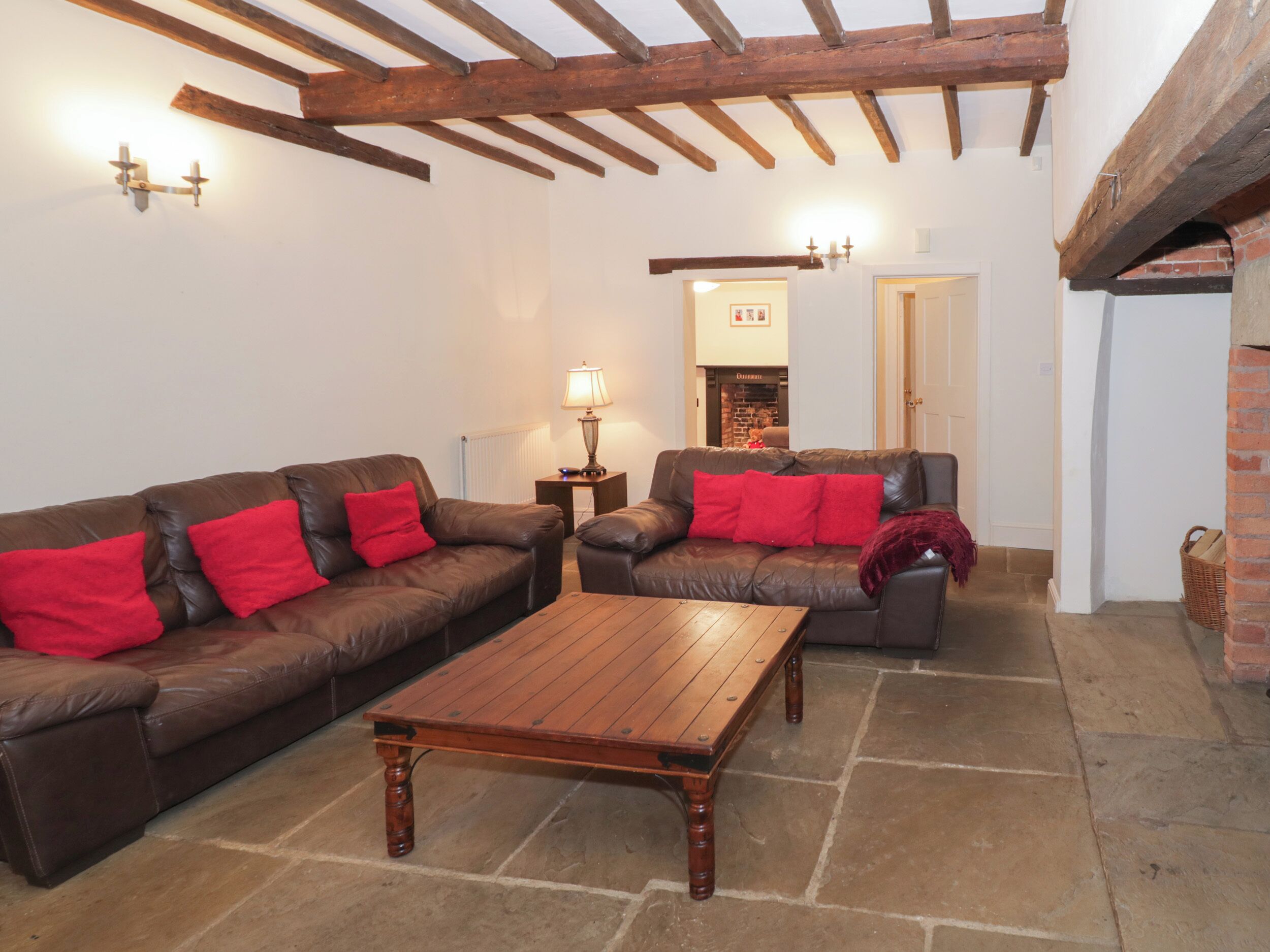 A cozy living room with two leather sofas, a wooden coffee table, and a brick fireplace.