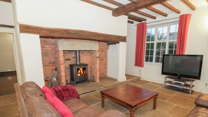 Una sala de estar con chimenea de ladrillo, sofás de cuero, una mesa de centro de madera y un televisor.