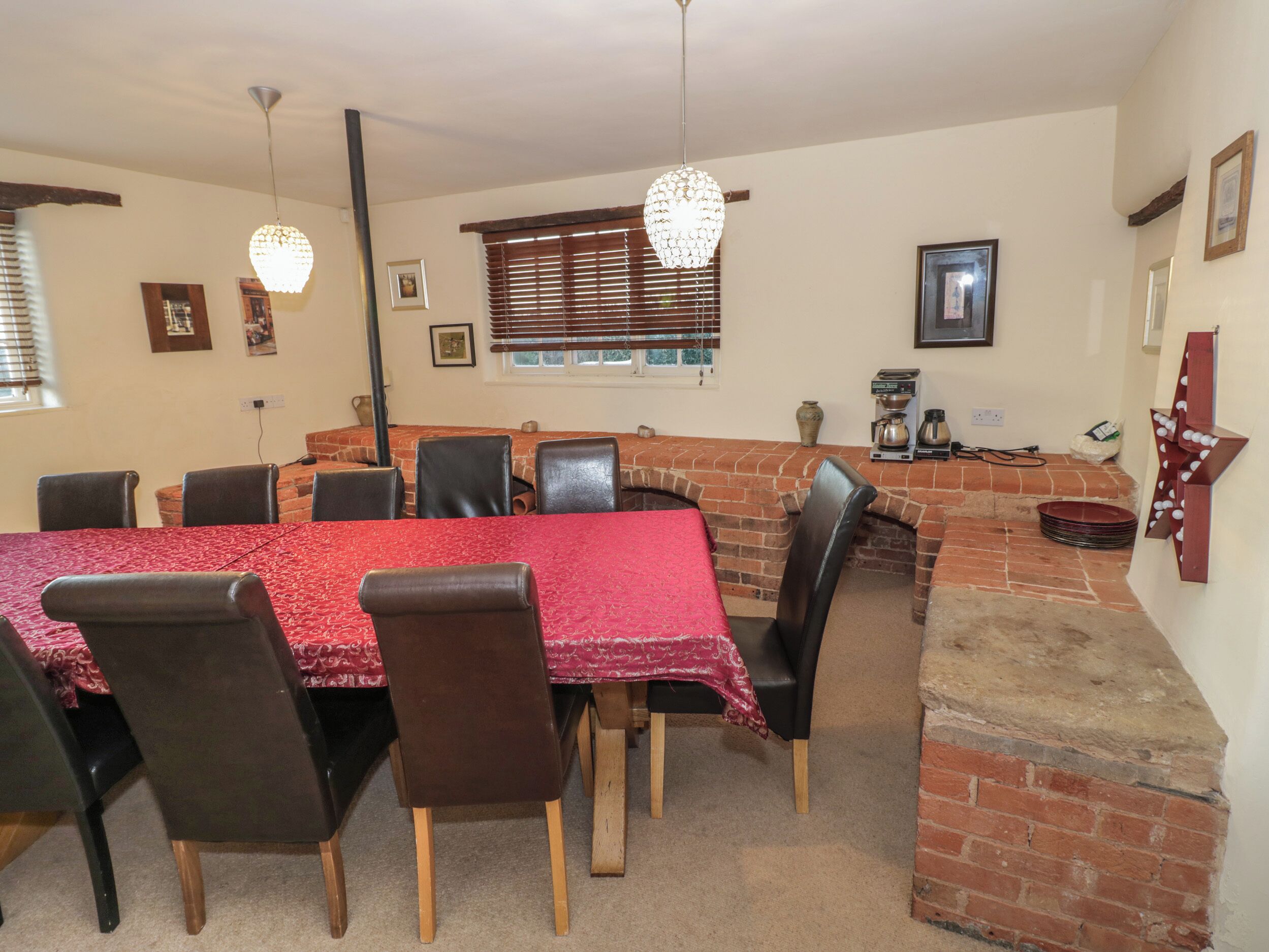 A dining area with a brick fireplace, red tablecloths, and black chairs.