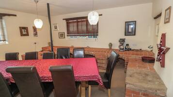 A dining area with a brick fireplace, red tablecloths, and black chairs.