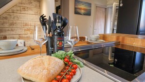 A kitchen with a loaf of bread, cherry tomatoes, and a bottle of Chianti wine on the counter. - Beacon House (Whitby)
