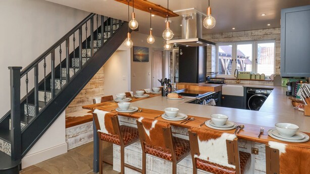 A modern kitchen with a central island, a staircase, and pendant lighting. - Beacon House (Whitby)