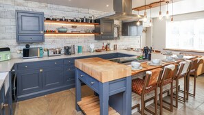 A modern kitchen with a central island, built-in cabinets, and pendant lighting. - Beacon House (Whitby)