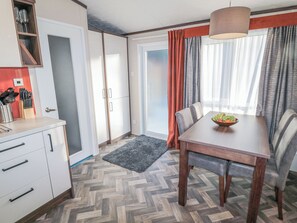 Une cuisine moderne avec des meubles blancs, un plan de travail en bois et un sol à motifs en chevrons.