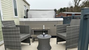 An outdoor patio with wicker furniture, a fire pit, and a hot tub. - Downtime Lodge (Morpeth)
