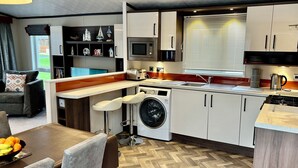 A compact kitchen with a washing machine, microwave, and a sink. - Downtime Lodge (Morpeth)