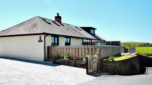 A two-story house with a sloped roof, a chimney, and a wooden fence.
