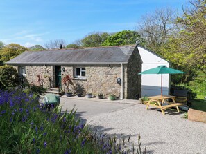 A stone cottage with a gravel driveway, a wooden bench, and a green umbrella. - Chy-an-oula (Falmouth)