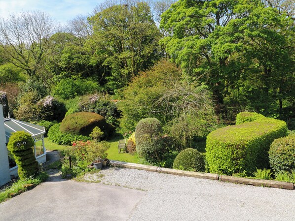 Un jardin bien entretenu, agrémenté de divers arbres et arbustes, et un chemin de gravier menant à un bâtiment.