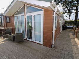 Una cabaña de madera con puerta corredera de vidrio, un patio con mobiliario de mimbre y una zona de terraza.