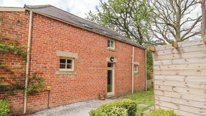 A brick building with a gravel driveway, a wooden fence, and green shrubs. - The Fullerton (Newcastle-upon-Tyne)