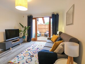 A living room with a sofa, TV, and a view to the outside. - The Annexe at Number 4 (Norwich)