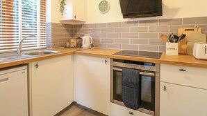 Una cocina moderna con un lavamanos, estufa, horno y un reloj en la pared.