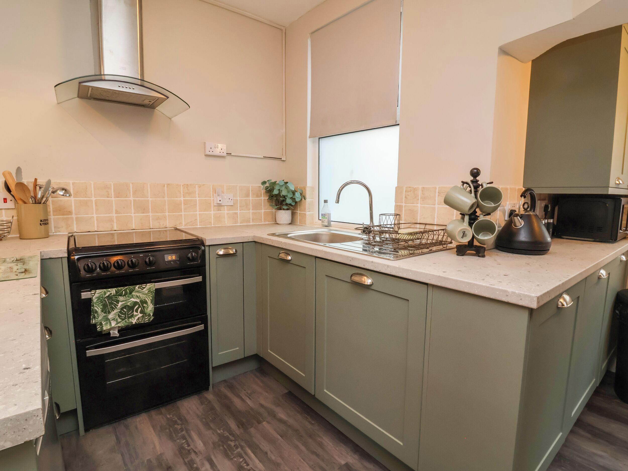 A kitchen with a stove, oven, sink, and a microwave.