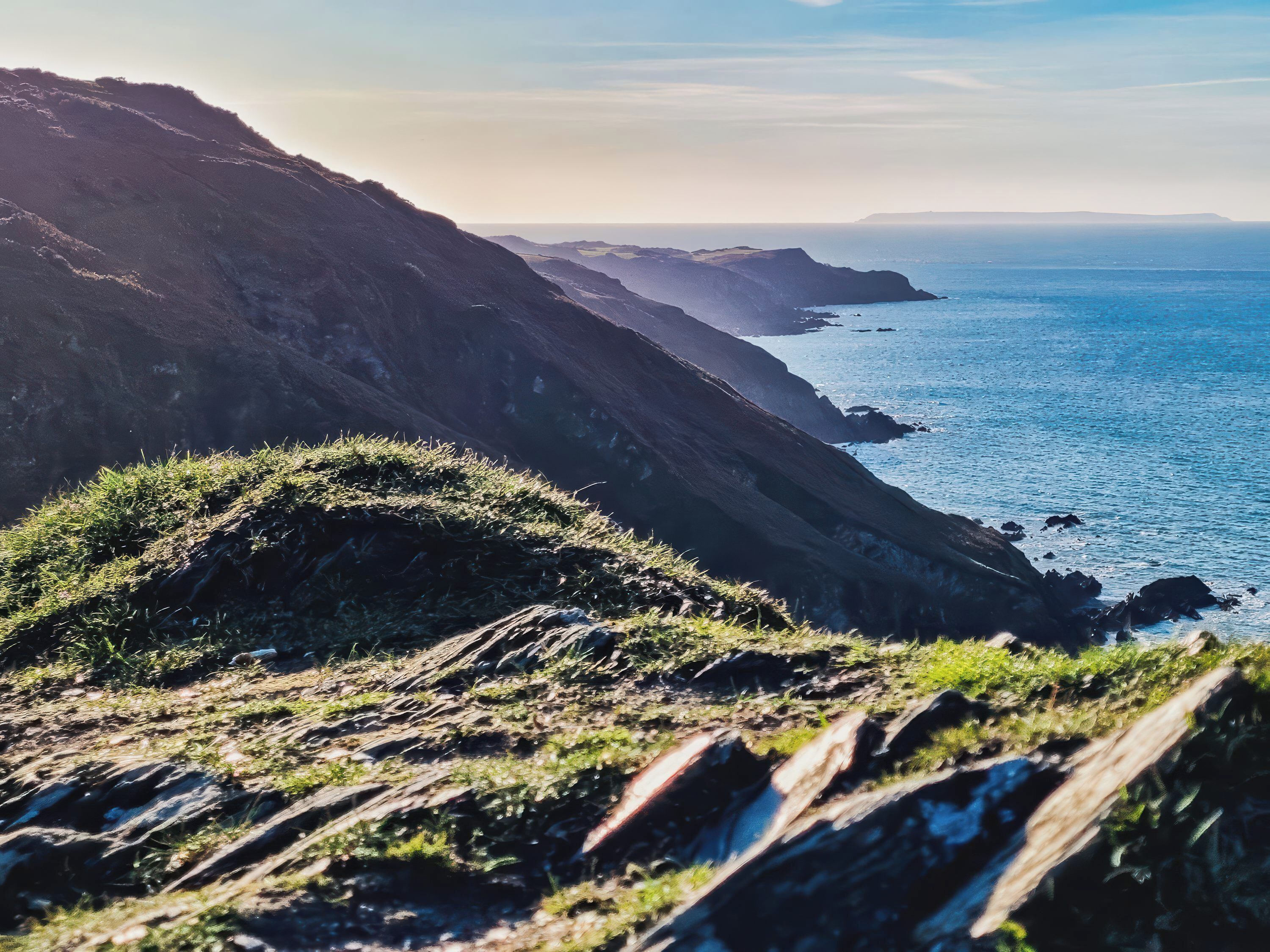 A coastal landscape with rocky terrain and a view of the ocean.