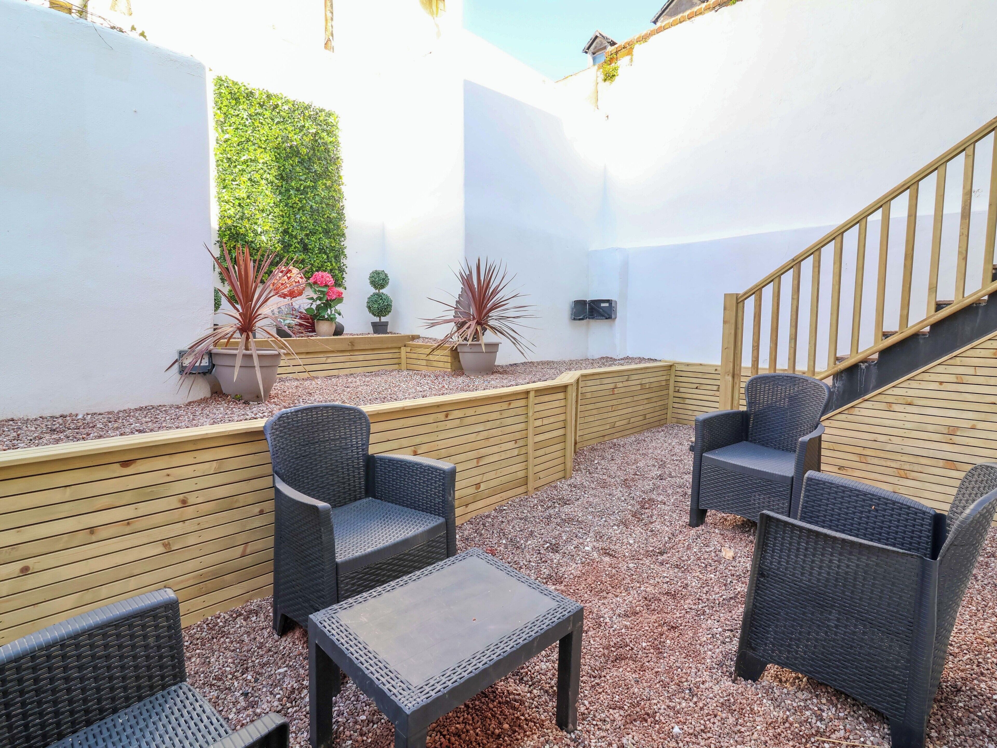 A patio area with wicker furniture, a wooden bench, and a small table.
