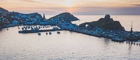 A coastal town with a prominent church, a lighthouse, and a marina with boats.