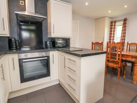 A compact kitchen with a built-in oven, microwave, and a coffee maker on the countertop.