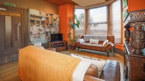A cozy living room with a sofa, a television, and a fireplace. - Mermaid's Rest (Newquay)