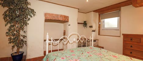 Une chambre à coucher avec un lit, une plante en pot, une commode en bois et une fenêtre.